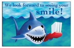 smiling shark post card with toothbrush and the phrase "we look forward to seeing your smile!" 